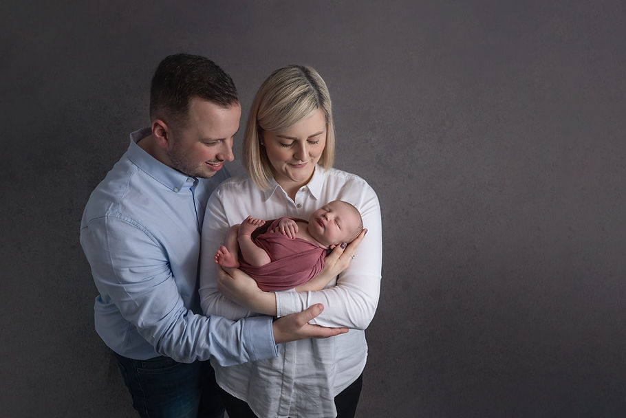 Loving parents looking down at their baby girl during newborn photoshoot with Lisburn phot